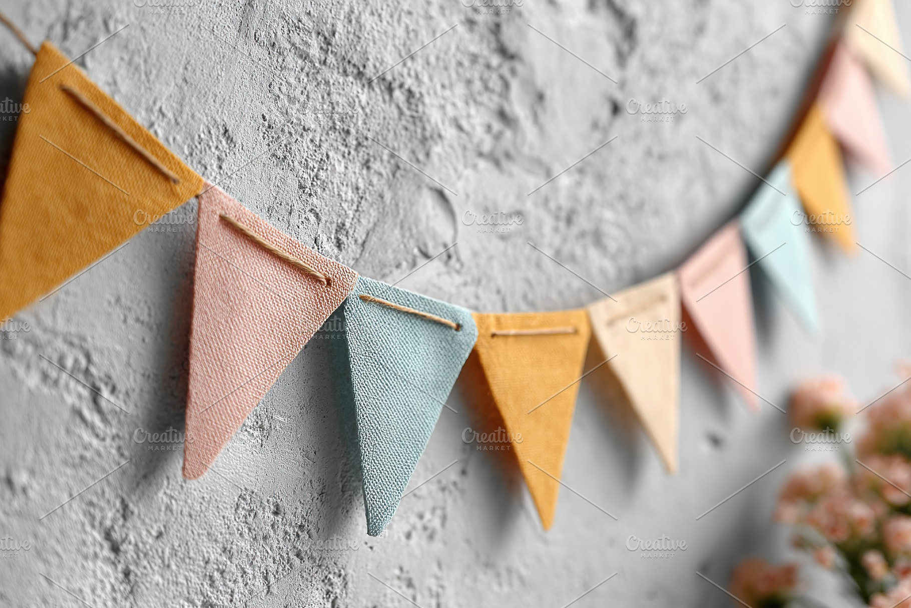 Colorful paper bunting flags hanging against a textured wall at a festive gathe, a Background Photo by AlyaAnd