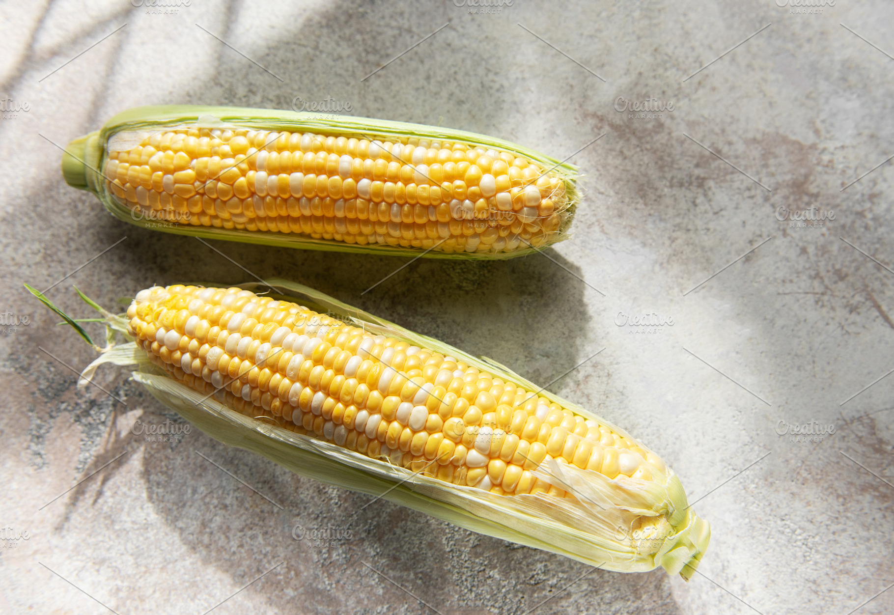 Fresh corn cobs on concrete background, a Food & Drink Photo by Olena Rudo