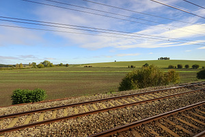 Railway tracks passing through green rural landscape under blue, a Photo by Studio ANNA
