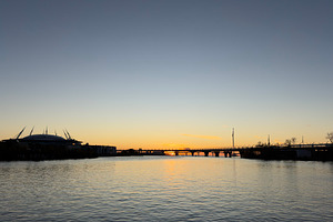A serene sunset over a river, with silhouettes of buildings and a bridge in the, a Nature Photo by Textures & Backgrounds