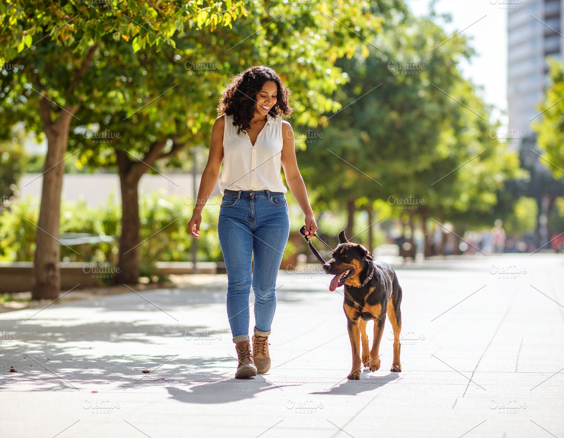 Woman walking her dog on a city sidewalk, a Person Photo by DanFLCreativo