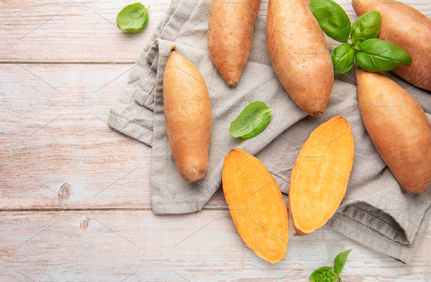 Raw sweet potatoes on wooden background preparing healthy meal, a Food & Drink Photo by Olena Rudo