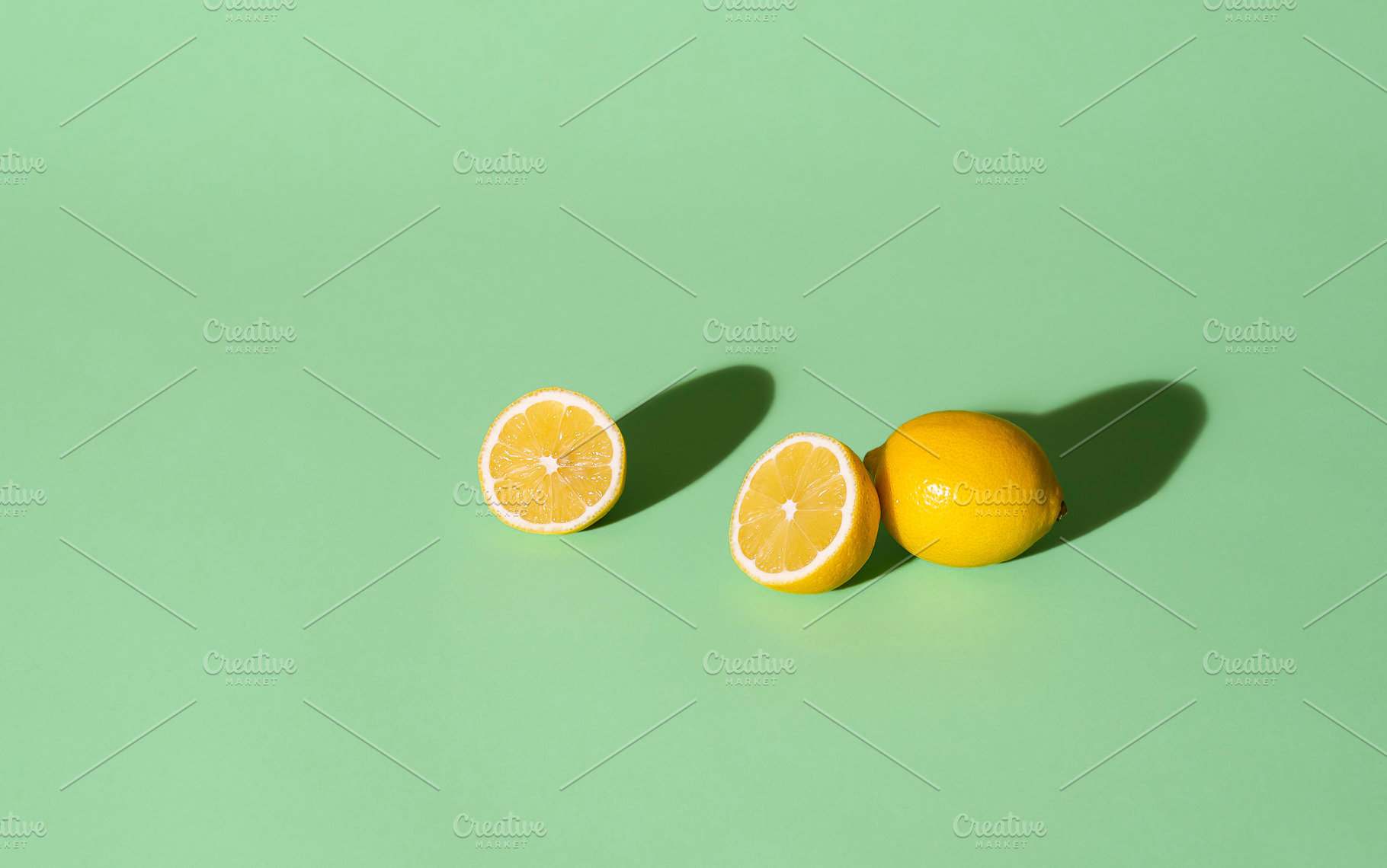 Fresh lemons cut in half on a green, a Food & Drink Photo by YesPhotographers