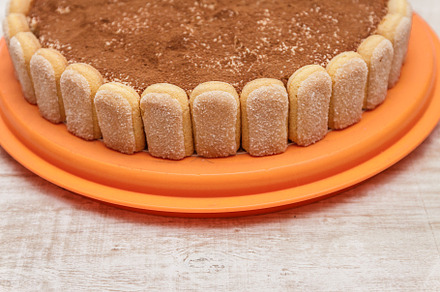 Round tiramisu cake on white wood table sprinkle with cacao powd, a Food & Drink Photo by TanaCh