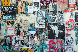 A Vibrant Urban Wall Covered With A Collage Of Posters, Stickers, And Graffiti.