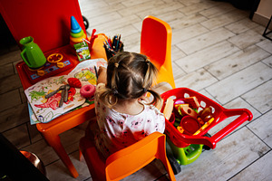 Young child playing with toys and drawing at a colorful children's activity tab, a Photo by AS photostudio