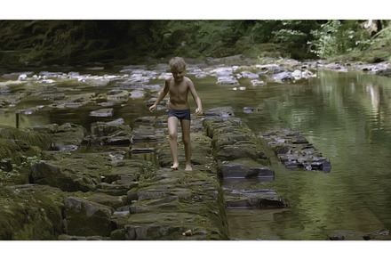 Boy walks on rocks in water in wild, a Person Photo by Media Whale Stock