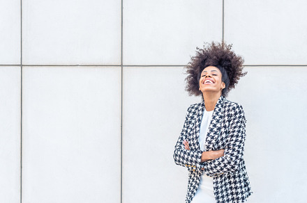 woman laughing wearing a plaid jacket and a white dress, a Business Photo by Iván Moreno STOCK PHOTO