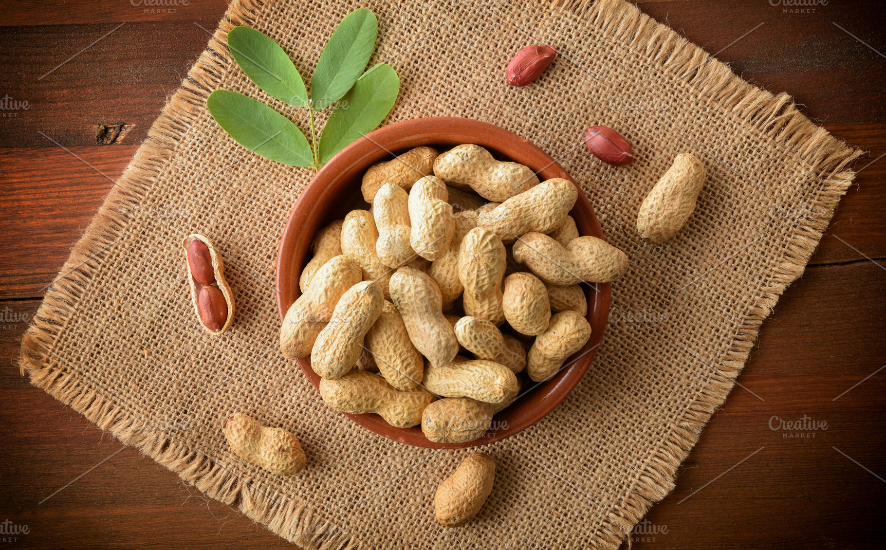 Handful of peanuts in container on sackcloth mat on wooden, a Food & Drink Photo by Davizro's Market