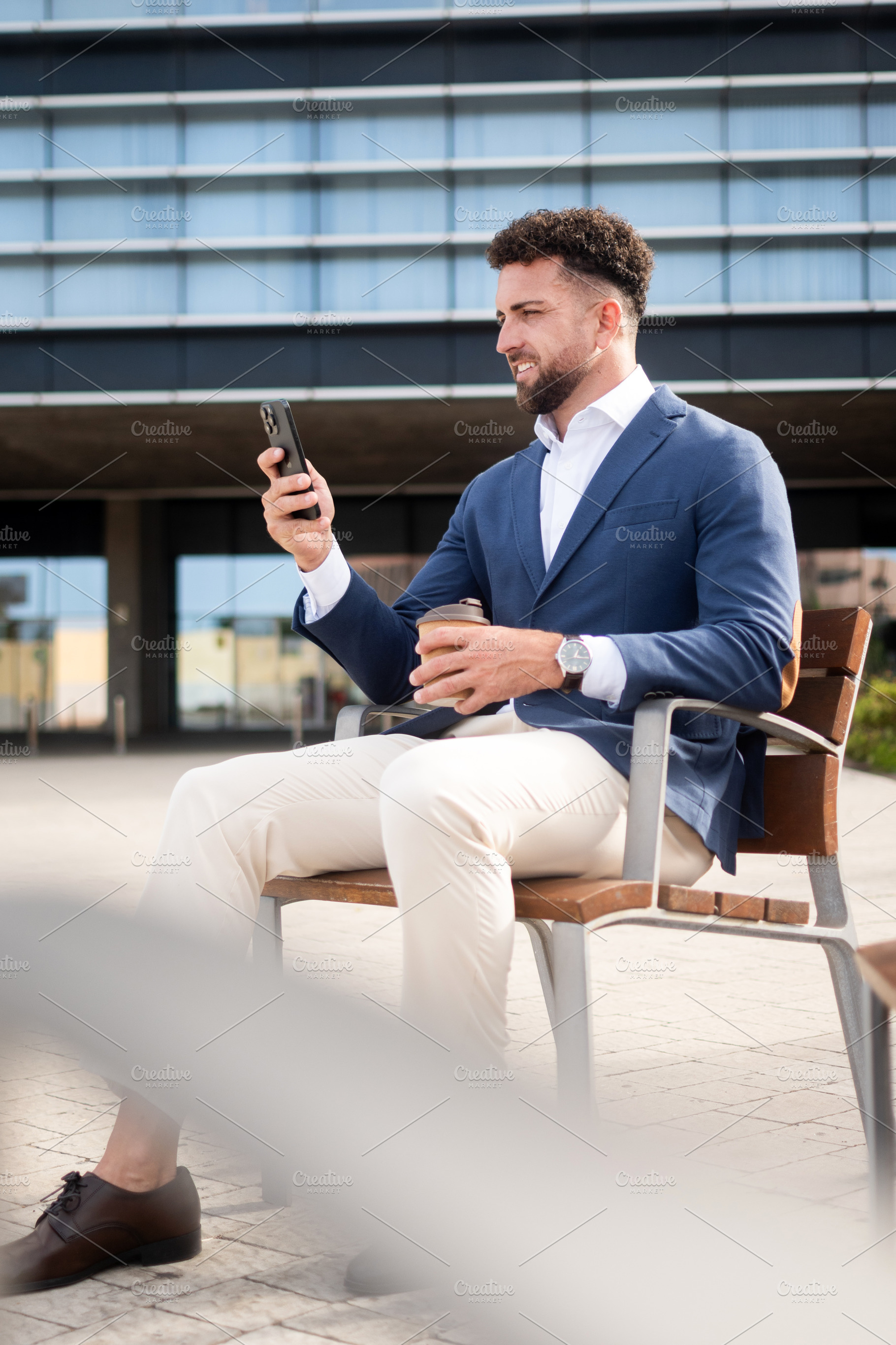Businessman checking smartphone during coffee break outside office, a Business Photo by etorres69