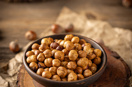 Shelled hazelnuts in a bowl placed on a wooden board