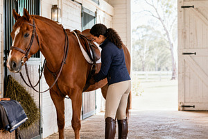 Woman preparing chestnut horse for r