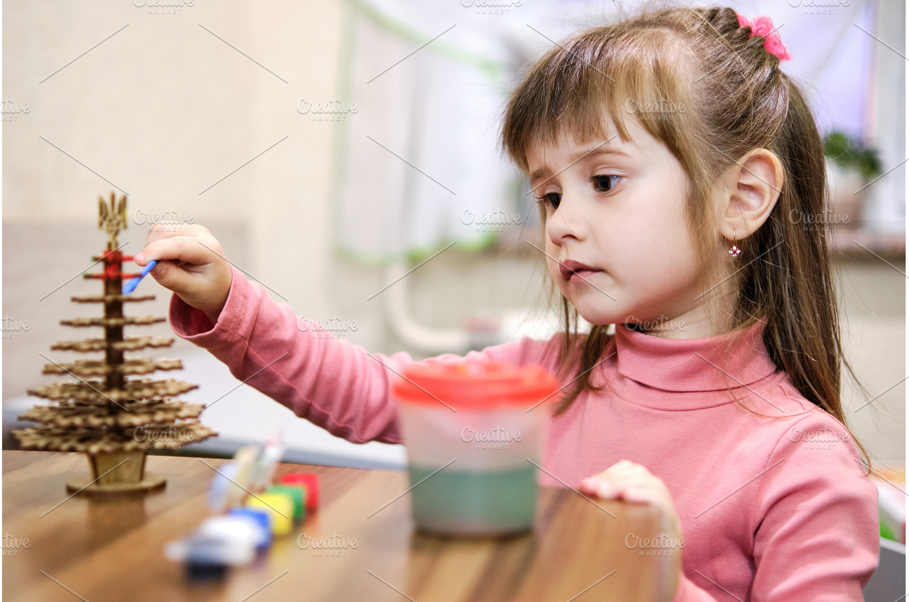 A little girl paints a wooden toy in, a Holiday Photo by Rohan Photography