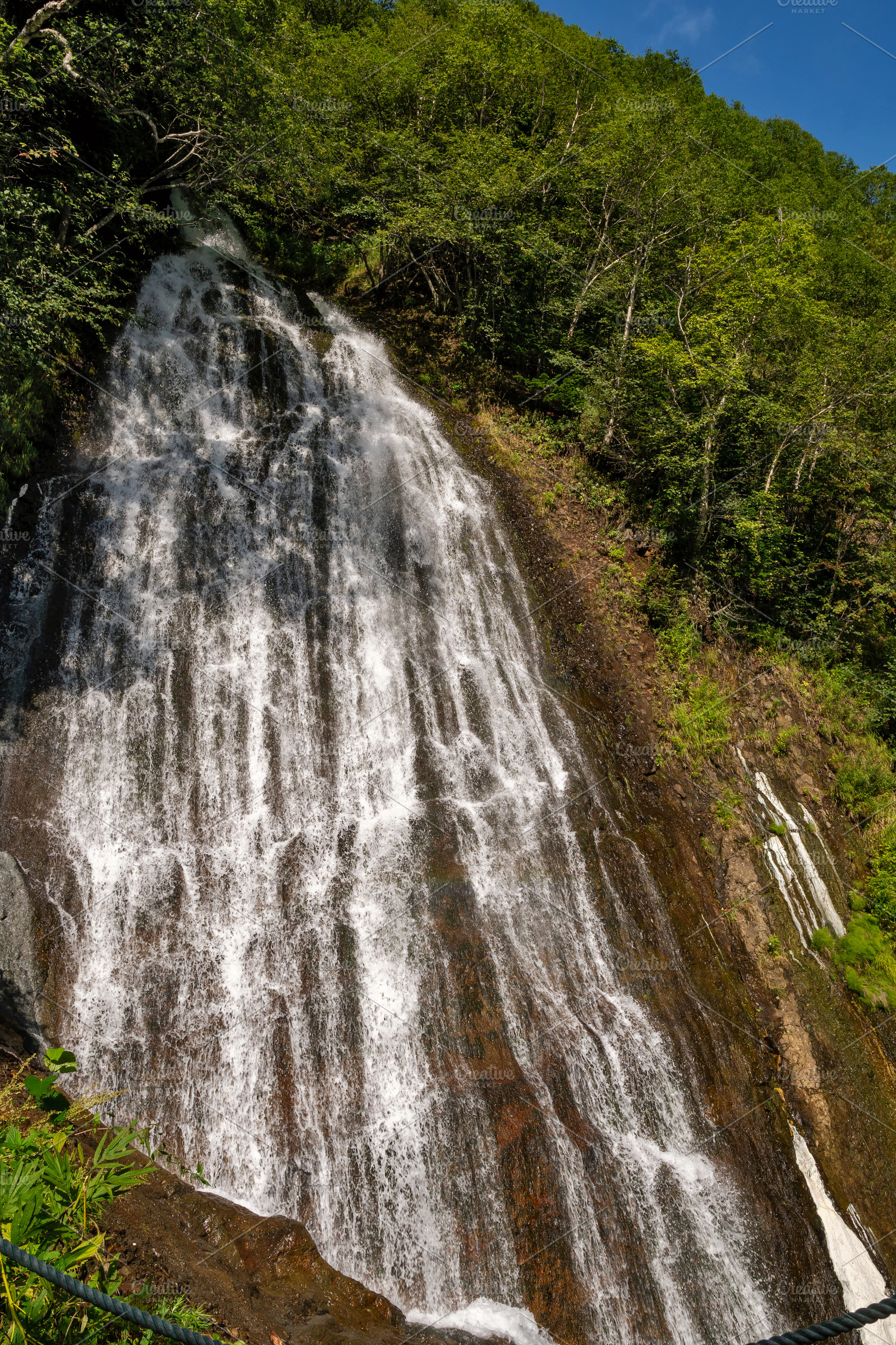 Tall waterfall cascading down rocky, a Nature Photo by Elena Vagengeim