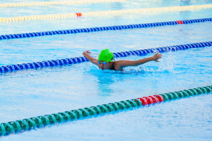 Swimmer child swims butterfly swimming style in a race swimming, a Health & Medical Photo by Casanowe-studio