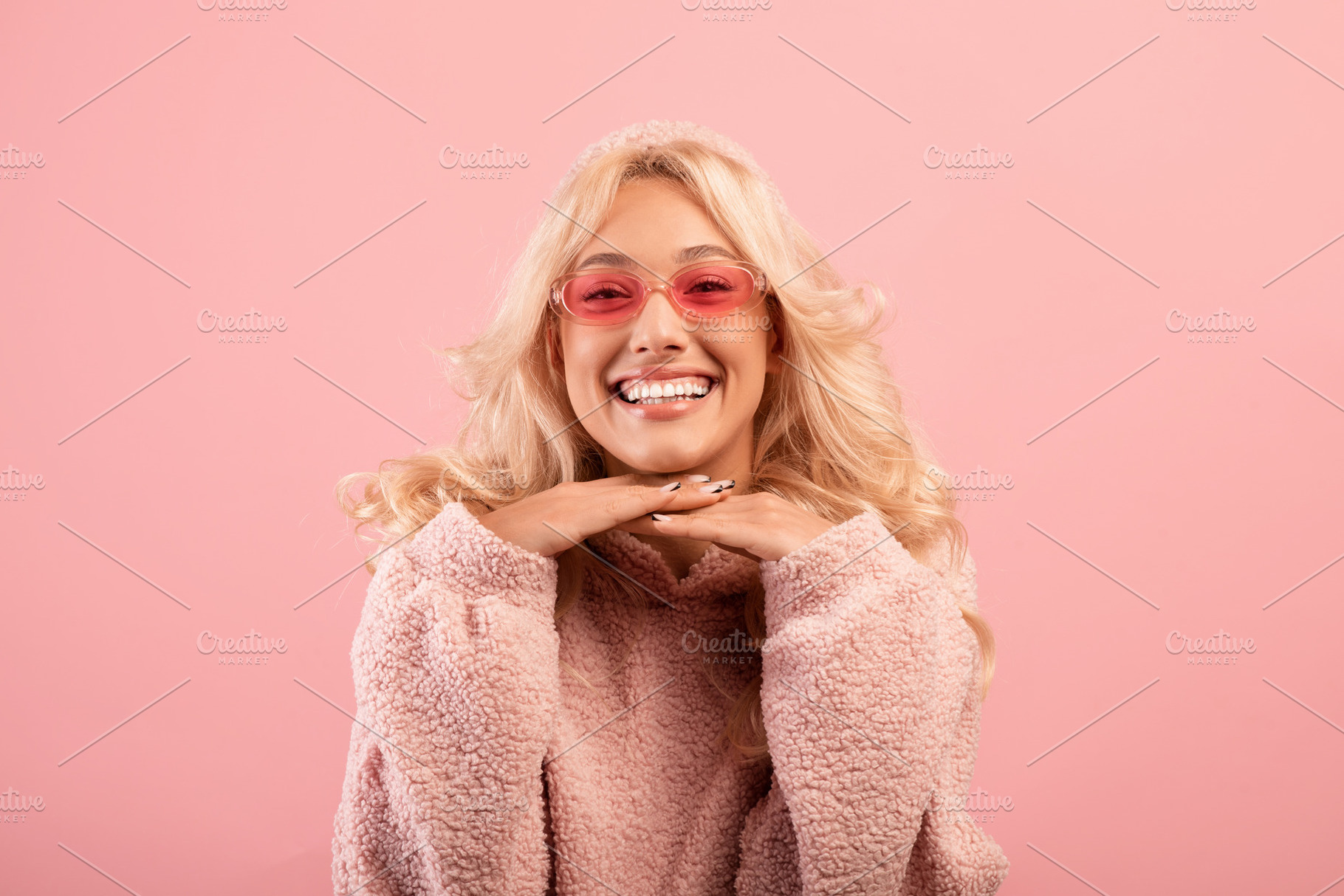 Joyful pretty lady leaning chin on hands and smiling at camera, posing over pin, a Photo by Prostock-Studio