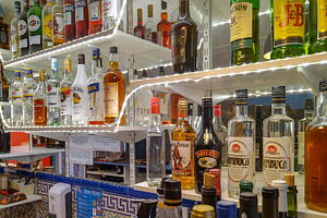 Shelves fully stocked with liquor bottles at a bar, a Food & Drink Photo by DanFLCreativo