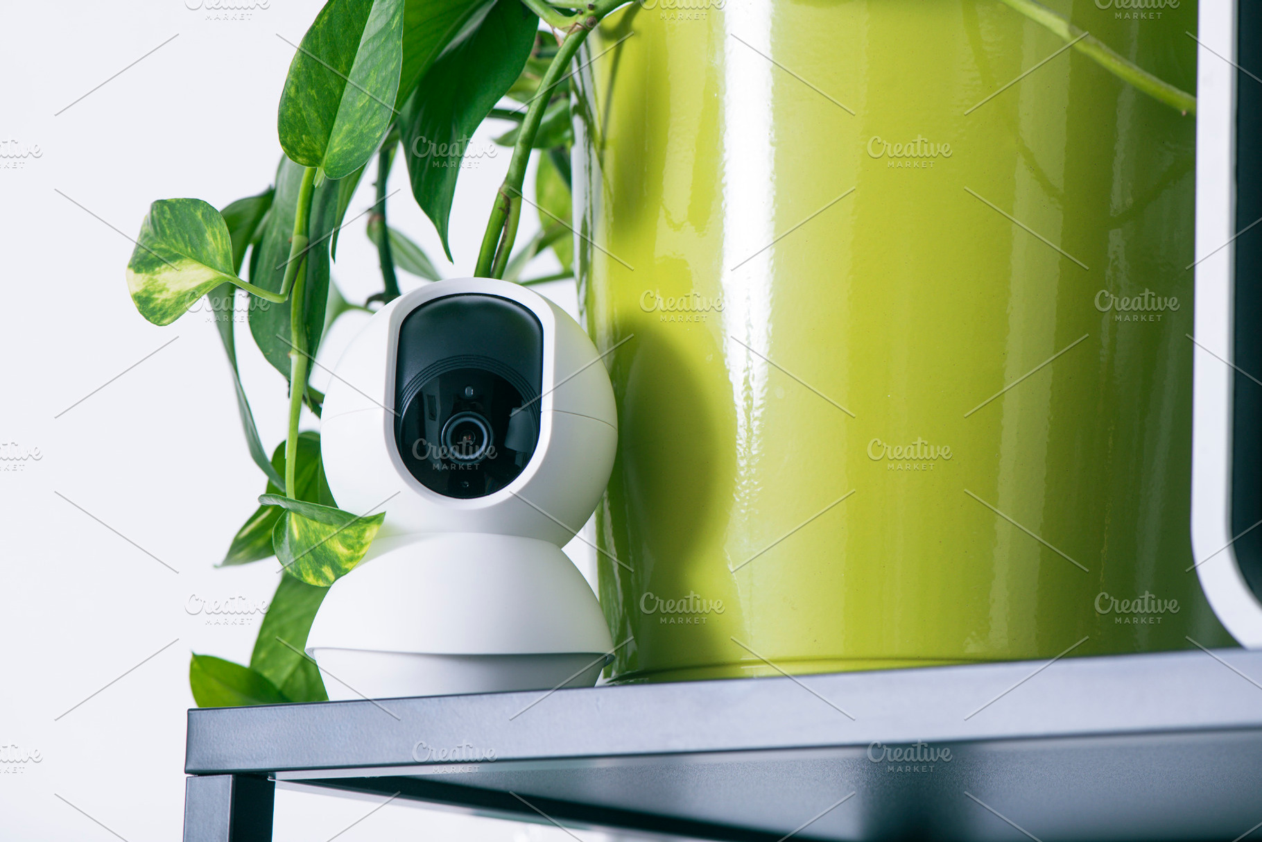 a security camera next to a green plant pot, a Photo by Nito