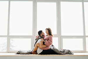 A couple in love sits on the windowsill. Newlyweds having fun.