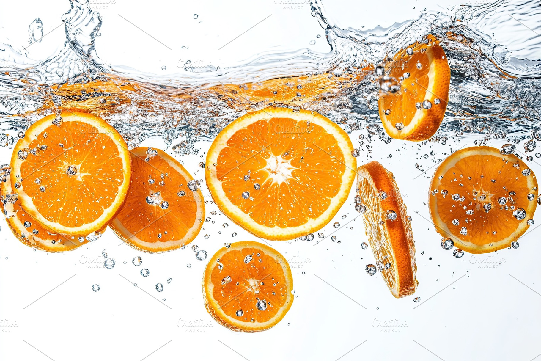 Sliced orange falling into water on white background, a Food & Drink Photo by AlyaAnd