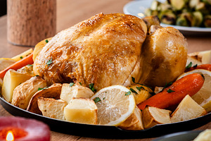 Whole roasted chicken with potatoes and vegetables.