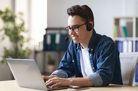Telecommuting Concept. Young Male Manager In Headset Working With Laptop In Off