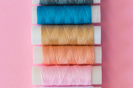 Thread spools with pink background featuring thread, spool, and embroidery