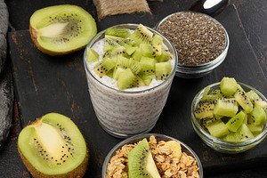 Glass of chia seed pudding mixed with diced kiwi is on a black s, a Food & Drink Photo by ndanko