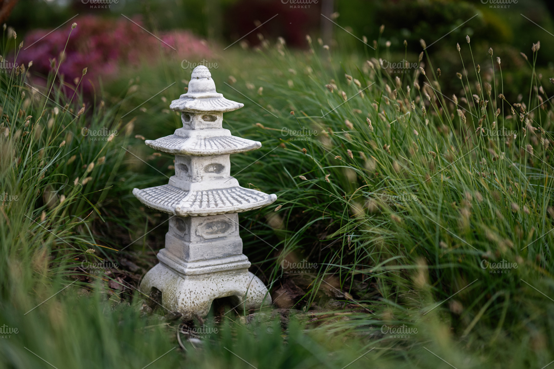 Serene stone pagoda sculpture amidst a lush garden landscape, a Photo by AS photostudio