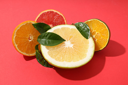Citrus fruits halves with leaves on red background, a Food & Drink Photo by AtlasStudio PRO