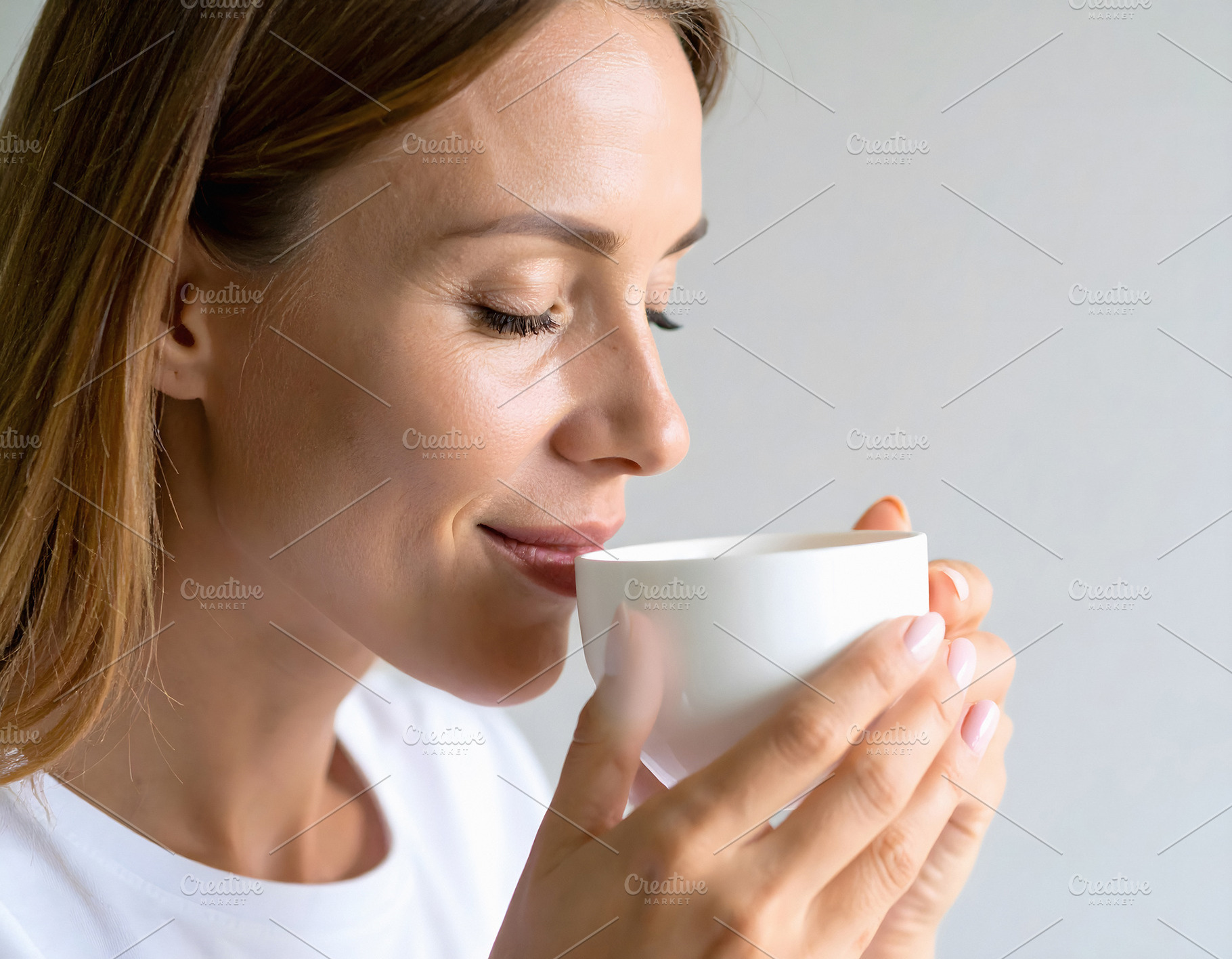 Woman holding tea cup with relaxed and serene smile, a Person Photo by GoodGoods