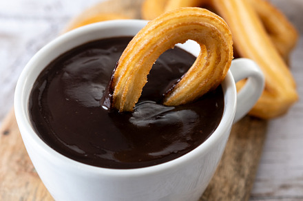 Traditional Spanish churros with hot chocolate breakfast on wooden table, a Food & Drink Photo by etorres69