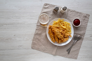 Homemade Chicken Strips with Fries on a Plate, top view. Space f, a Food & Drink Photo by LiudmylaChuhunova