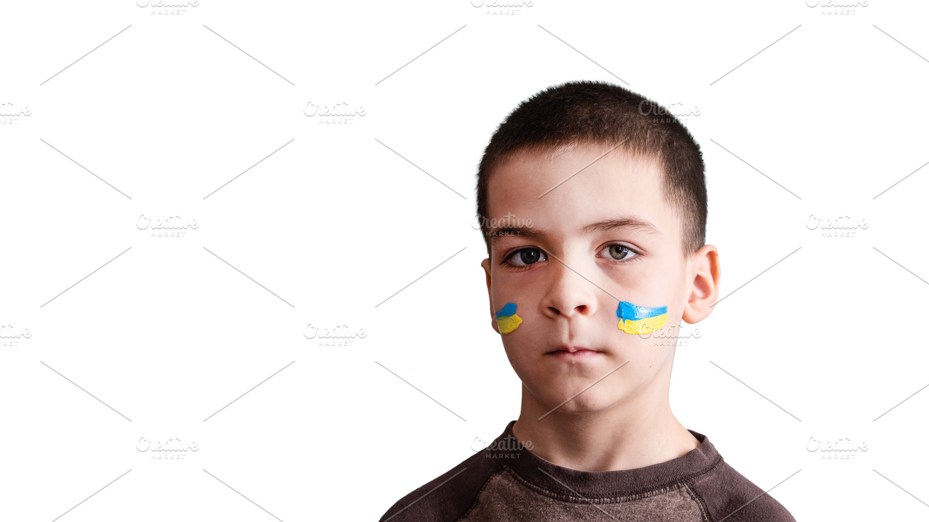 Child against war. Upset Ukrainian boy with bue yellow flag on his face, a Photo by OleksandrRybitskyi