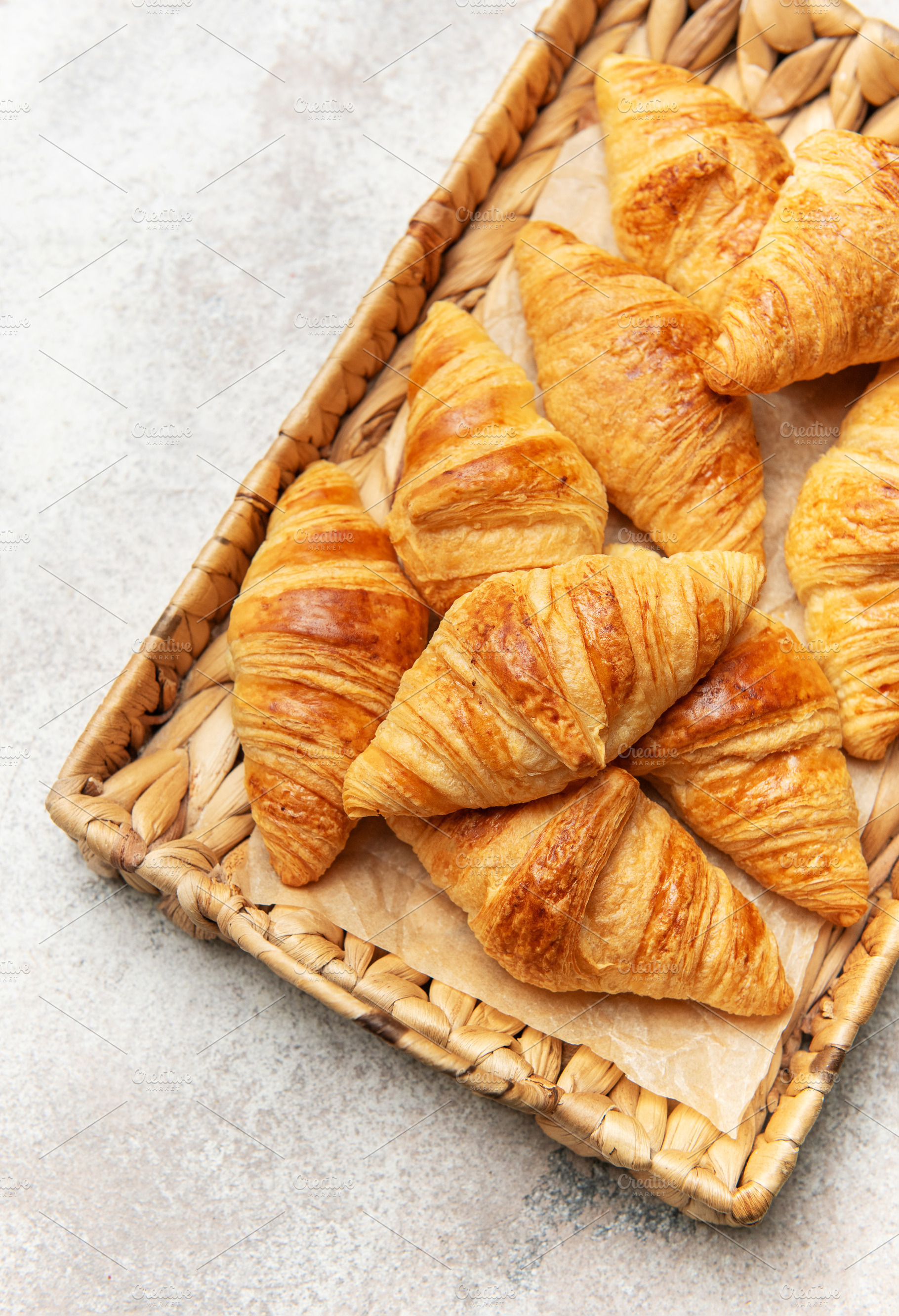 Freshly baked croissants resting on a wicker tray, a delightful, a Food & Drink Photo by Olena Rudo