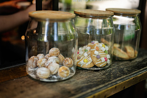 Glass jars filled with various delicious cookies on a wooden counter, a Photo by AS photostudio