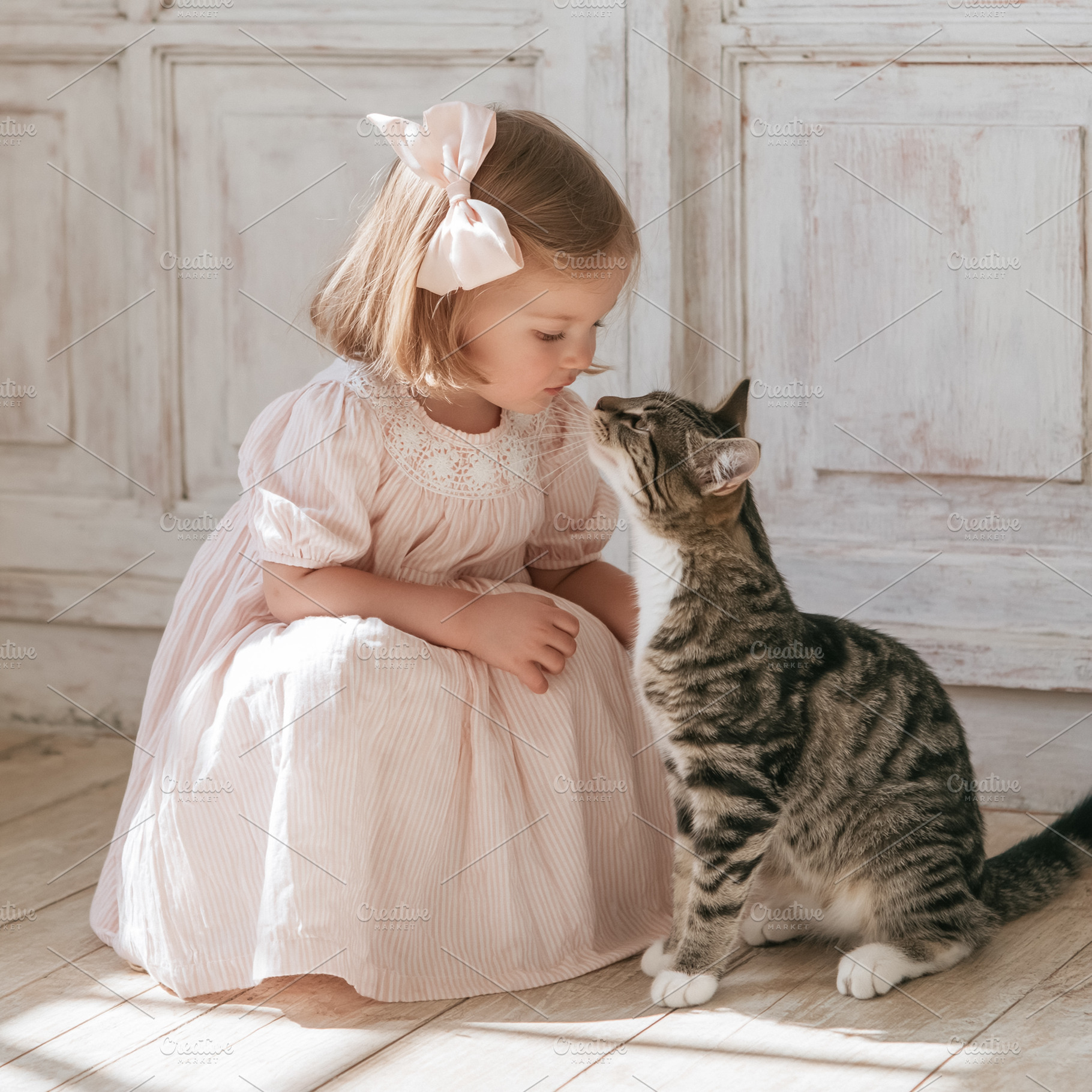 Little girl in striped dress bonding with a tabby cat, showing f, a Person Photo by Studio ANNA