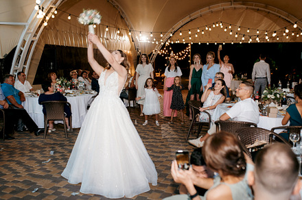 bride in a white dress throws a wedding bouquet