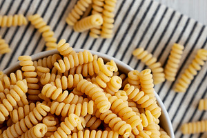 Uncooked Organic Dry Fusilli Pasta in a Bowl, top view. Flat lay, a Food & Drink Photo by LiudmylaChuhunova