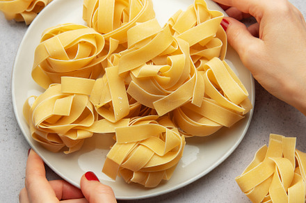 Chef placing uncooked pasta on white plate for italian cuisine, a Food & Drink Photo by Olena Rudo