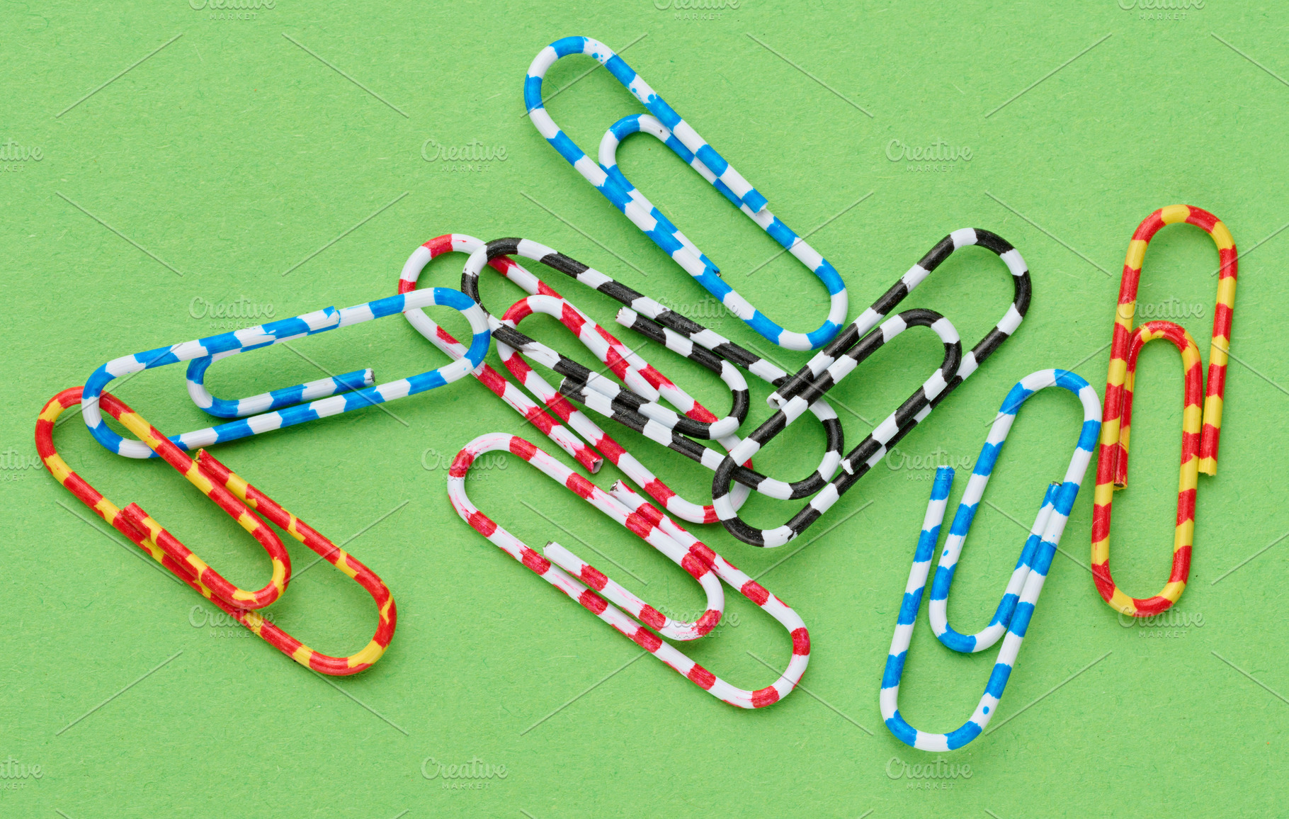 A handful of colorful striped paper clips lying haphazardly on a, a School & Education Photo by ndanko