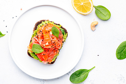 Avocado and salmon toast on rye bread with spinach leaves, cashe, a Food & Drink Photo by 5PH