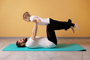 Happy father and young daughter practicing acro yoga on a mat in, a Person Photo by Ales Munt