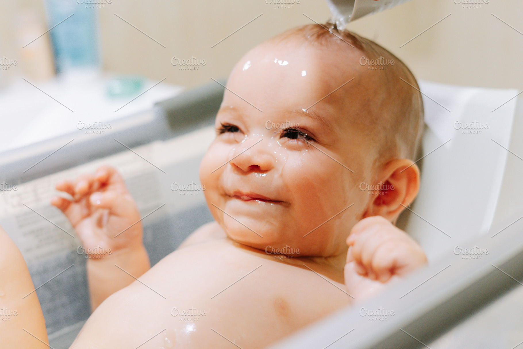 Portrait of a nine month old baby taking a bath with water running trough his f, a Person Photo by rubenchase