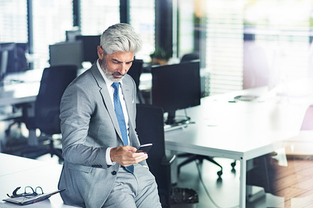Mature businessman with smartphone in the office stock photo containing desk, a Business Photo by HalfPoint