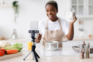 Smiling surprised millennial black female with open mouth in apron prepares lun, a Person Photo by Prostock-Studio
