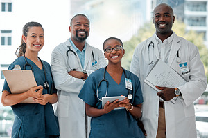 Group of doctors and nurses standing in a line with their arms crossed while working at a hospital. Content expert medical professionals smiling at work together at a clinic, a Photo by Peopleimages.com