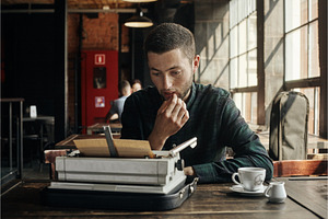 Young Man Writing On Old Typewriter.