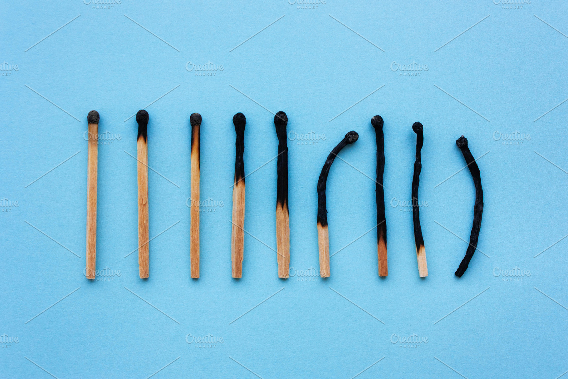 Burned matches in a row on a blue ba containing burned, matches, and concept, an Arts & Entertainment Photo by KulT design
