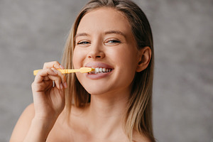 Healthy teeth and care. Happy lady brushing teeth with toothbrush and smiling a, a Photo by Prostock-Studio